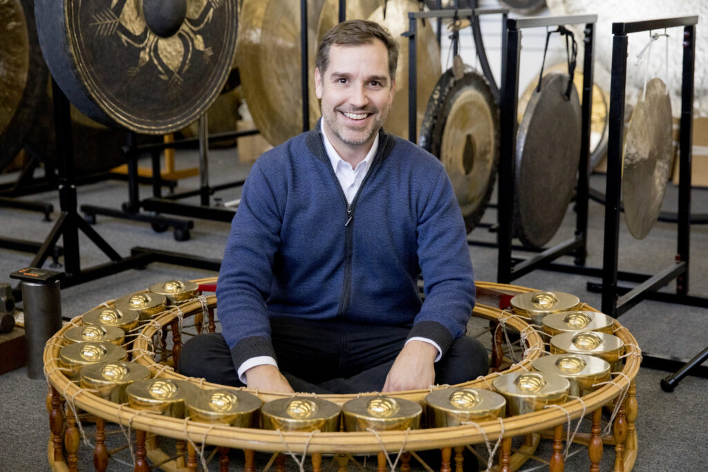Trey Wyatt, owner of The Gong Shop, surrounded by gongs in his showroom